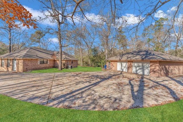 view of side of property with a garage, cooling unit, and a lawn