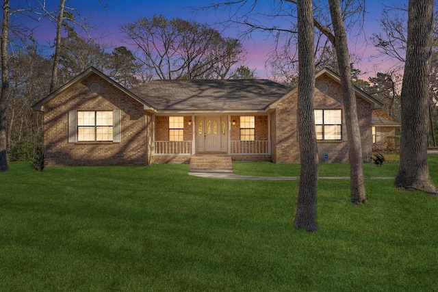 single story home featuring a porch and a lawn