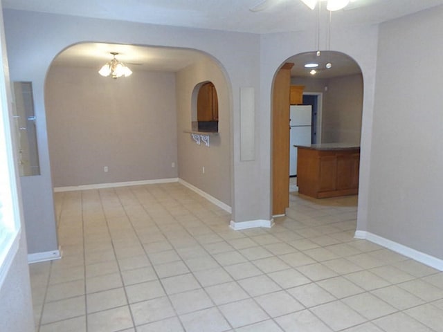 unfurnished room featuring light tile patterned floors and ceiling fan with notable chandelier