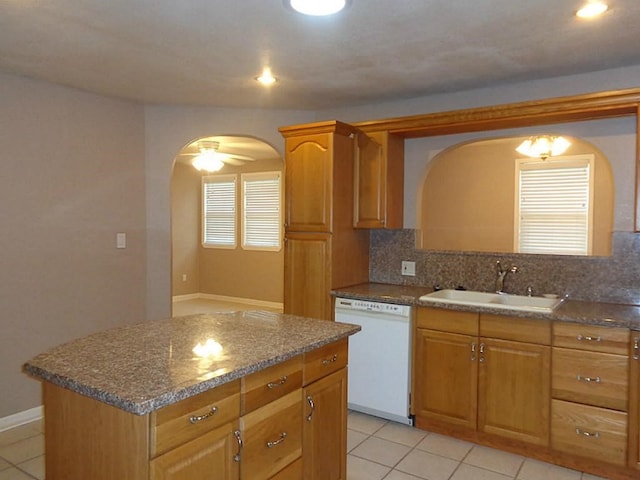 kitchen featuring ceiling fan, sink, white dishwasher, decorative backsplash, and a kitchen island