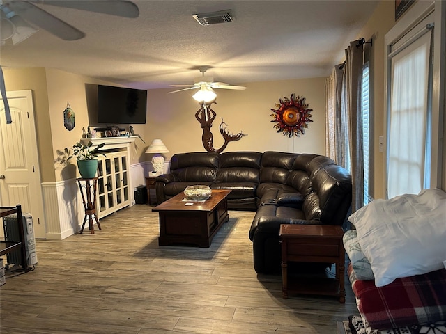 living room featuring a textured ceiling, light hardwood / wood-style floors, and ceiling fan