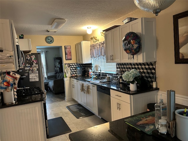 kitchen featuring stainless steel dishwasher, a textured ceiling, sink, white cabinetry, and light tile patterned flooring