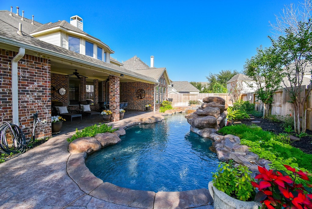 view of pool featuring ceiling fan, pool water feature, and a patio