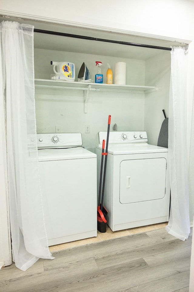 laundry room with washing machine and dryer and light wood-type flooring