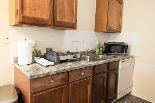 kitchen with white dishwasher, dark hardwood / wood-style floors, sink, and tasteful backsplash