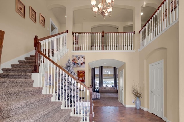 carpeted foyer with a towering ceiling and a notable chandelier