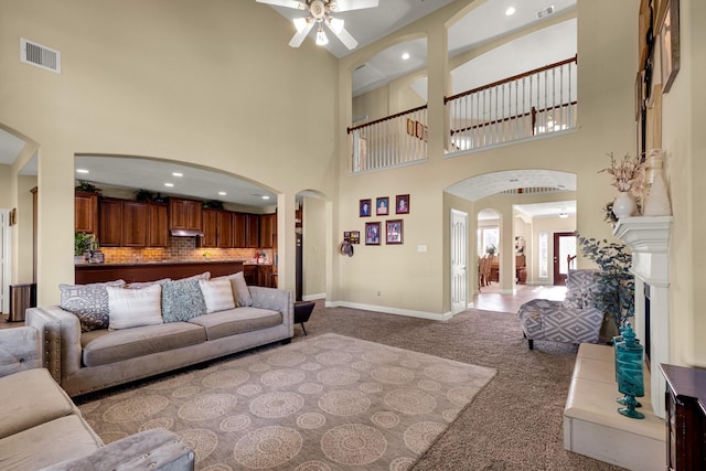 carpeted living room with ceiling fan and a towering ceiling