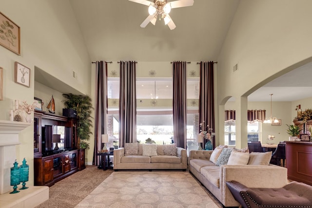 living room featuring high vaulted ceiling, light colored carpet, and ceiling fan with notable chandelier