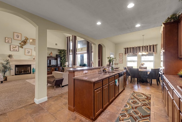 kitchen with light carpet, stainless steel dishwasher, decorative light fixtures, an inviting chandelier, and a center island with sink