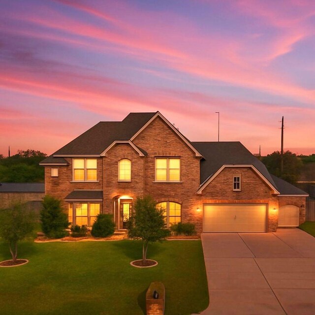 11411 Kings Point Blvd, Mont Belvieu, TX 77535 - traditional home featuring a front yard, concrete driveway, a garage, and brick siding