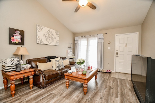 living room with hardwood / wood-style flooring, ceiling fan, and vaulted ceiling