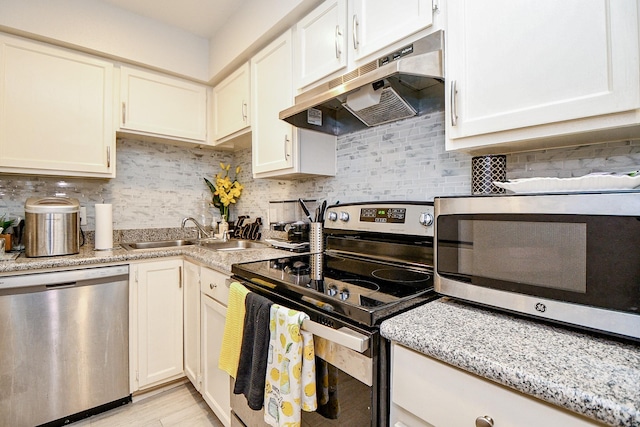 kitchen with backsplash, light stone countertops, sink, and stainless steel appliances