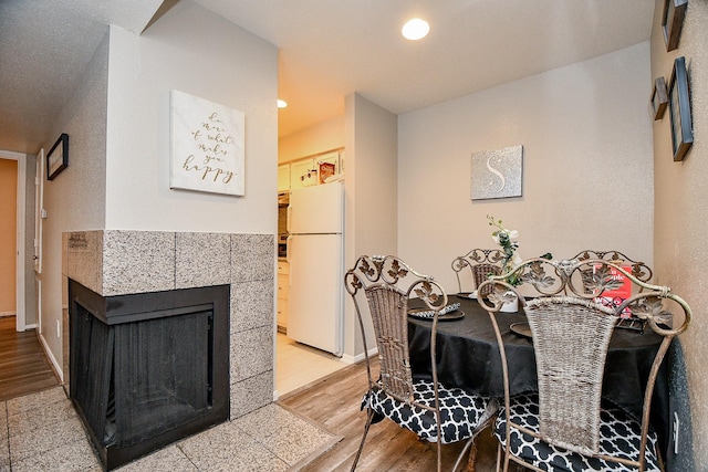 dining space featuring a tile fireplace and light hardwood / wood-style floors