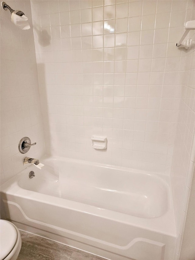 bathroom featuring toilet and tiled shower / bath