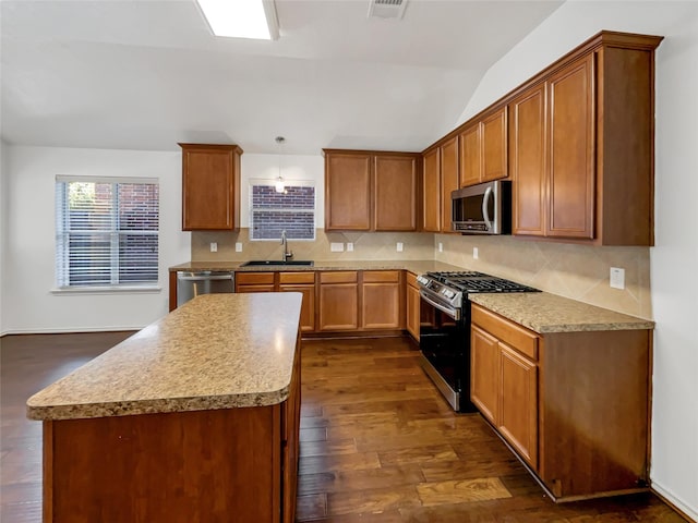 kitchen featuring sink, dark wood-type flooring, pendant lighting, vaulted ceiling, and appliances with stainless steel finishes