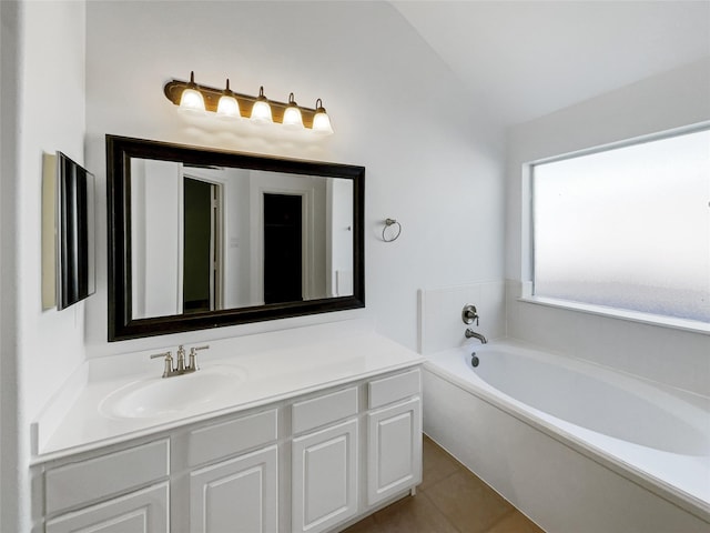 bathroom with tile patterned floors, a washtub, vanity, and vaulted ceiling