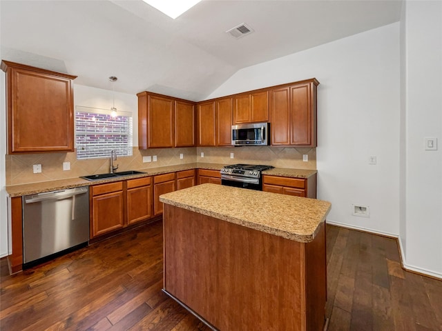 kitchen featuring pendant lighting, sink, vaulted ceiling, appliances with stainless steel finishes, and dark hardwood / wood-style flooring