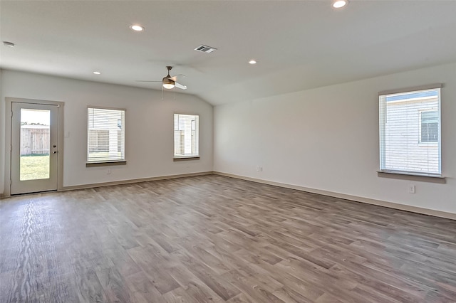 spare room with a healthy amount of sunlight, lofted ceiling, and light wood-type flooring