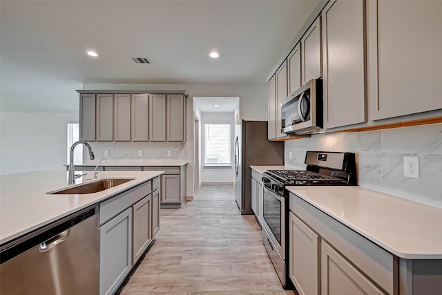 kitchen with gray cabinetry, light hardwood / wood-style floors, sink, and stainless steel appliances