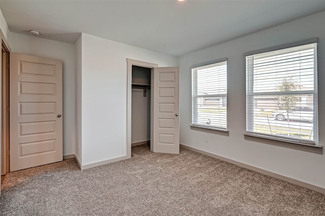 unfurnished bedroom featuring a closet, multiple windows, and light colored carpet