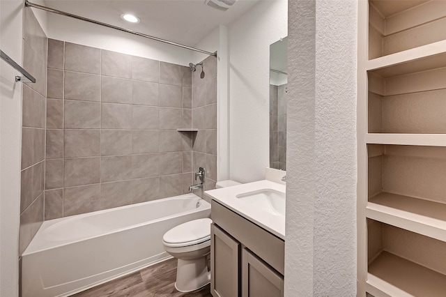 full bathroom featuring built in features, hardwood / wood-style floors, toilet, vanity, and tiled shower / bath