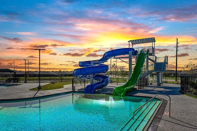 pool at dusk featuring a water slide