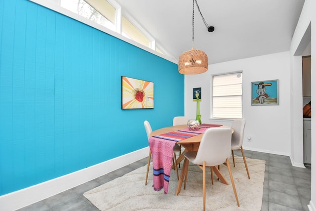 dining room with concrete floors, wooden walls, and vaulted ceiling