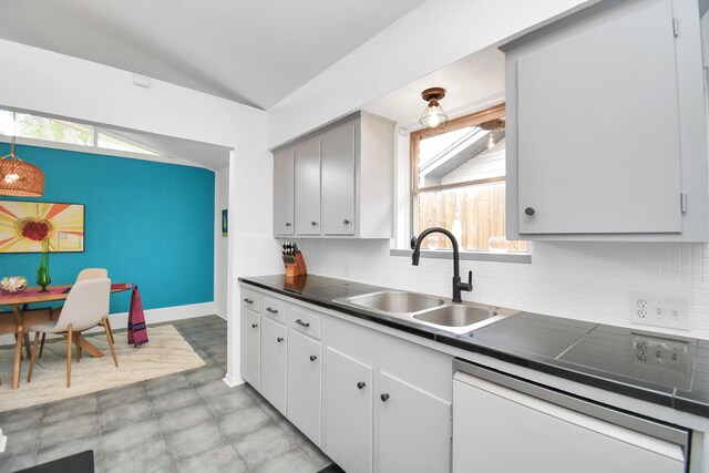 kitchen featuring white dishwasher, a healthy amount of sunlight, sink, and vaulted ceiling