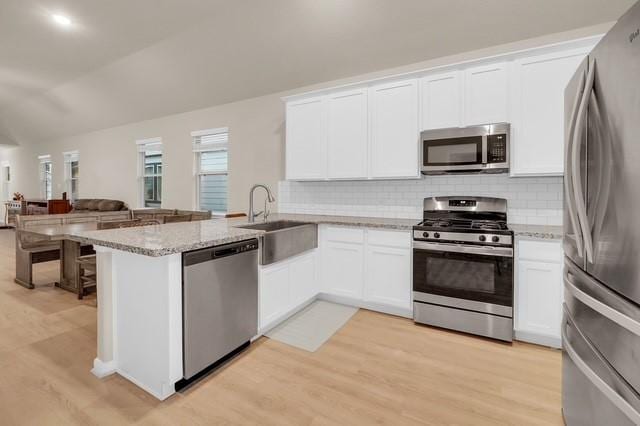 kitchen with sink, stainless steel appliances, light hardwood / wood-style flooring, kitchen peninsula, and white cabinets