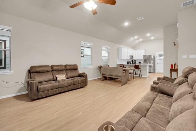 living room featuring ceiling fan, lofted ceiling, and light hardwood / wood-style flooring