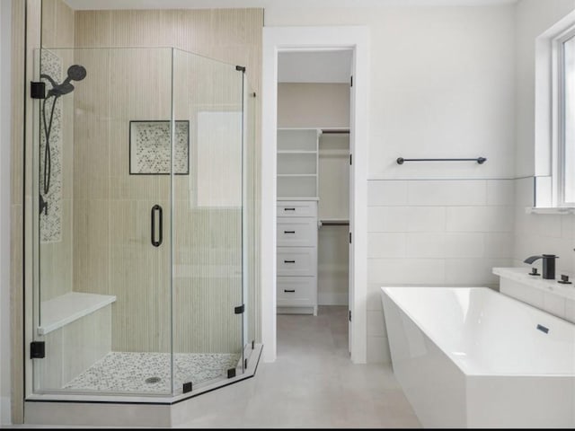 bathroom featuring separate shower and tub and tile walls