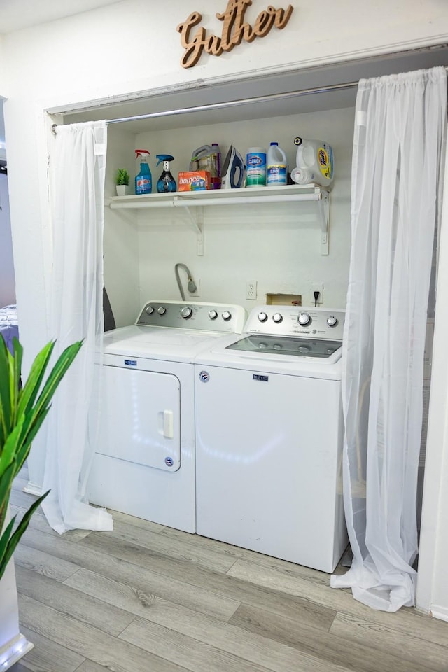 clothes washing area with washing machine and dryer and light hardwood / wood-style flooring