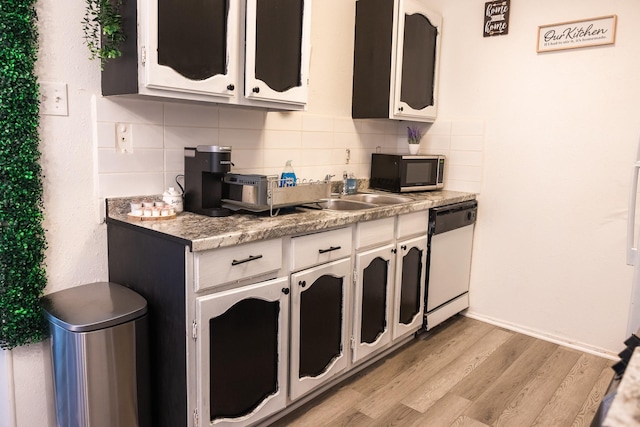 kitchen featuring white dishwasher, sink, light wood-type flooring, tasteful backsplash, and white cabinetry