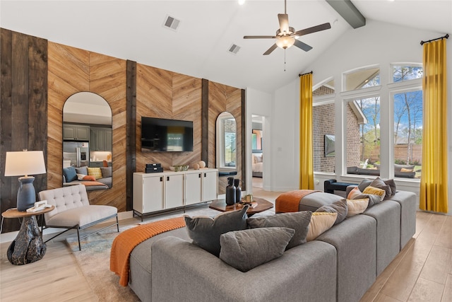 living room with a wealth of natural light, ceiling fan, and wood walls