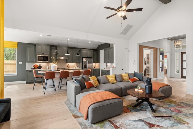 living room with light hardwood / wood-style flooring, high vaulted ceiling, and ceiling fan with notable chandelier