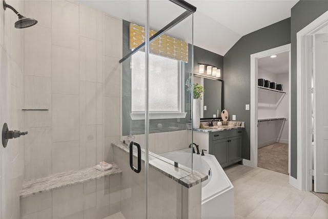 bathroom featuring separate shower and tub, vanity, and vaulted ceiling