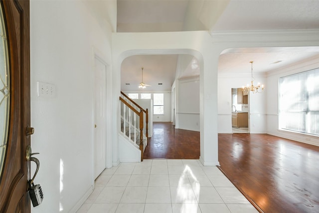 foyer featuring light hardwood / wood-style flooring, ceiling fan with notable chandelier, and ornamental molding