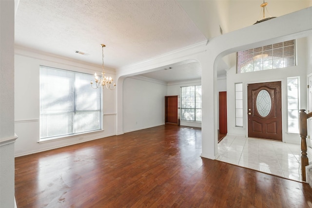 foyer featuring a textured ceiling, light hardwood / wood-style flooring, a wealth of natural light, and a notable chandelier