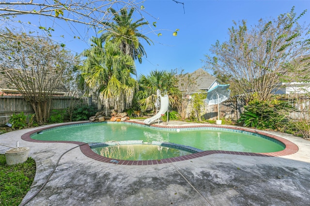 view of swimming pool with an in ground hot tub and a water slide