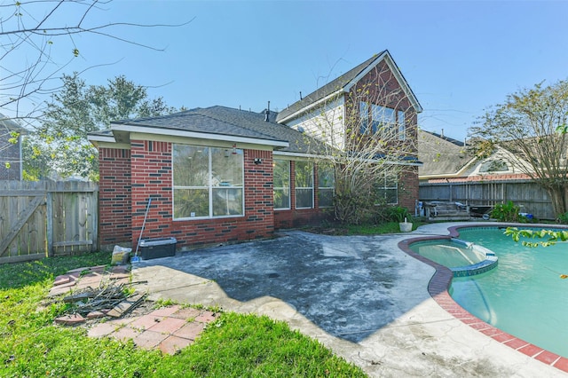 rear view of property with a fenced in pool and a patio