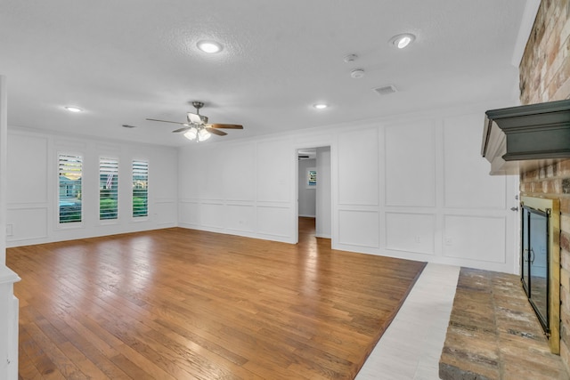 unfurnished living room featuring a fireplace, wood-type flooring, and ceiling fan