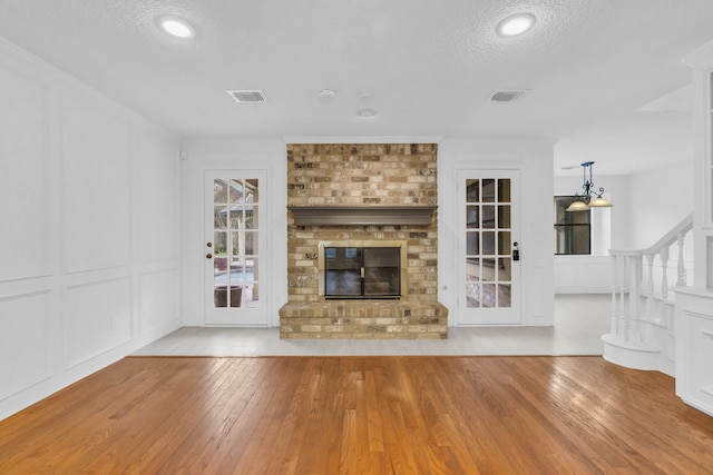 unfurnished living room featuring a brick fireplace, light hardwood / wood-style floors, and a textured ceiling