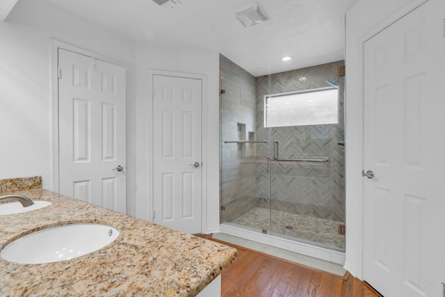 bathroom featuring hardwood / wood-style flooring, vanity, and a shower with shower door