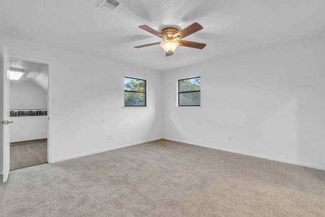 spare room with light colored carpet, a textured ceiling, and ceiling fan