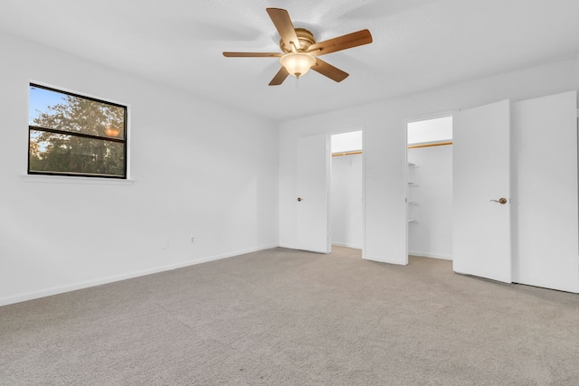 unfurnished bedroom featuring multiple closets, light carpet, and ceiling fan