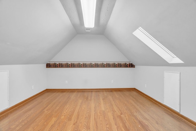 bonus room featuring vaulted ceiling with skylight and light hardwood / wood-style flooring