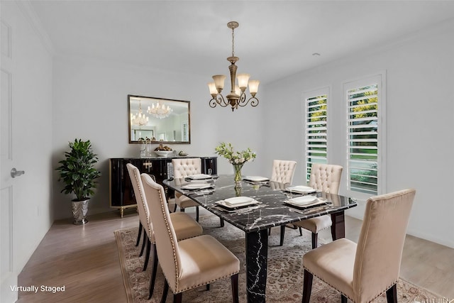 dining room with hardwood / wood-style flooring, ornamental molding, and an inviting chandelier