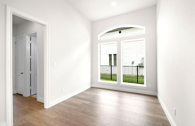unfurnished room featuring baseboards, a wealth of natural light, and wood finished floors