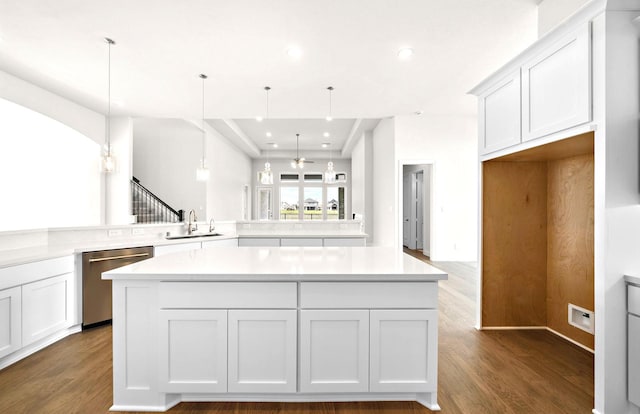 kitchen featuring stainless steel dishwasher, a sink, dark wood-style flooring, and a center island