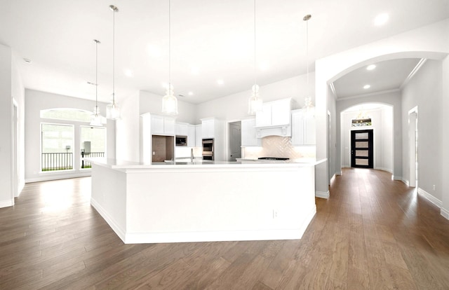 kitchen with white cabinets, light countertops, arched walkways, stainless steel appliances, and wood finished floors